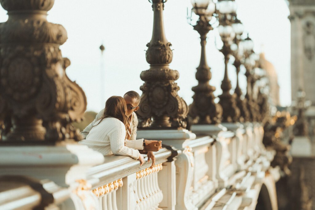 Couple près des balustrades du pont Alexandre III, avec les candélabres en arrière-plan